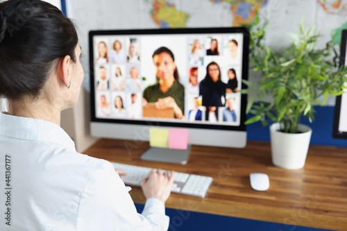 Woman communicating with group of business people via video conferencing