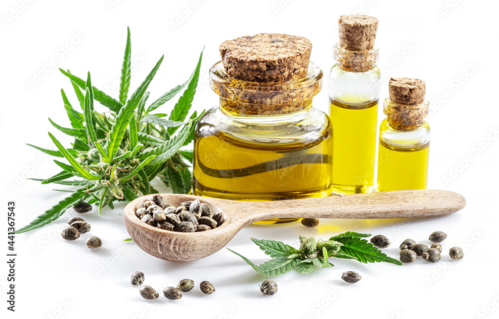 Cannabis seeds in the wooden spoon and bottles of hemp oil isolated on white background. Close up. Cannabis seeds in the wooden spoon and bottles of hemp oil isolated on white background. Close up.
