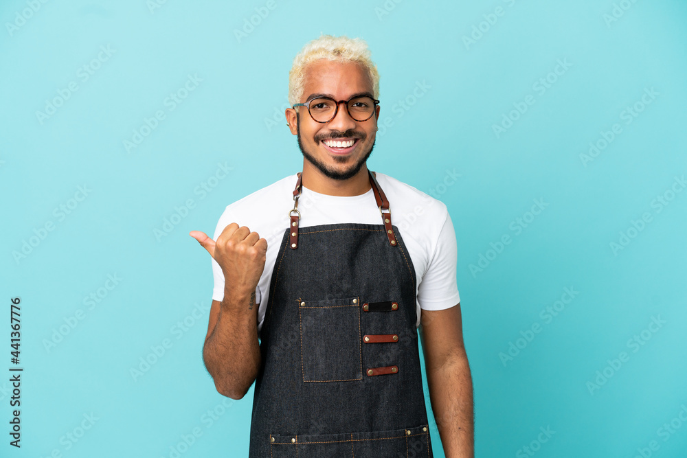 Restaurant Colombian waiter man isolated on blue background pointing to the side to present a product Restaurant Colombian waiter man isolated on blue background pointing to the side to present a product