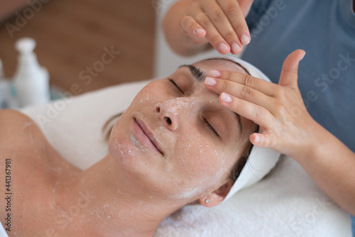 Cleaning and moisturise nourish skin of face. Cosmetologist make massage of face. Beautiful woman receives facial peeling. Treatment skin care in cosmetology beauty spa salon.