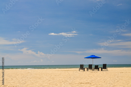 Beautiful beach on a sunny day with a row of beach lounger under a vibrant blue parasol