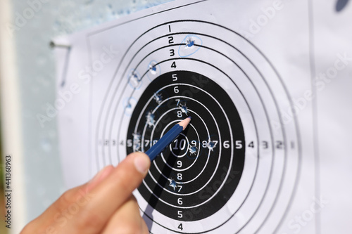 Man showing with pencil to shots on paper target closeup