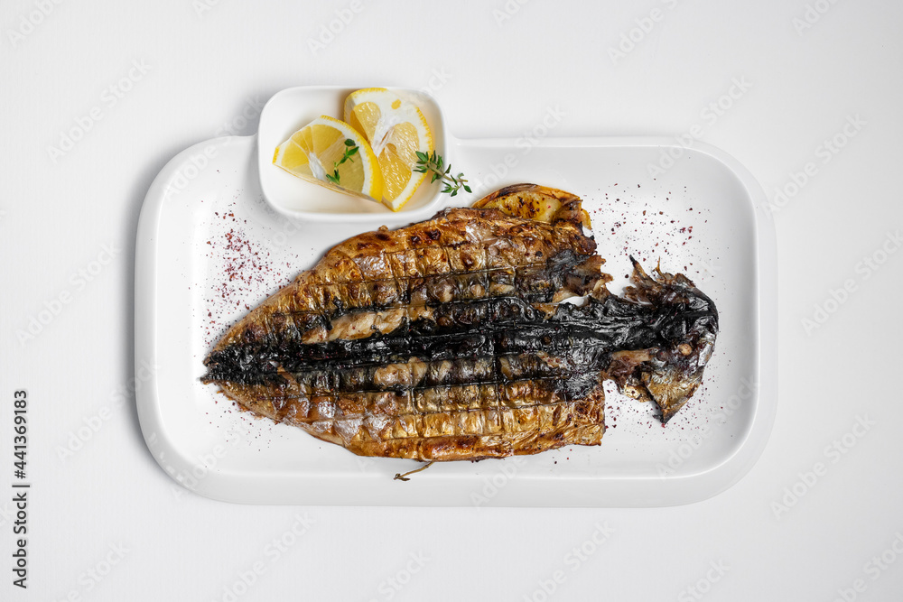 top view of grilled mackerel fish with lemon on plate on white background top view of grilled mackerel fish with lemon on plate on white background