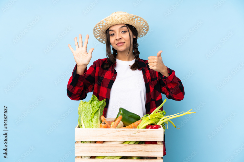 Young farmer Woman holding fresh vegetables in a wooden basket counting six with fingers