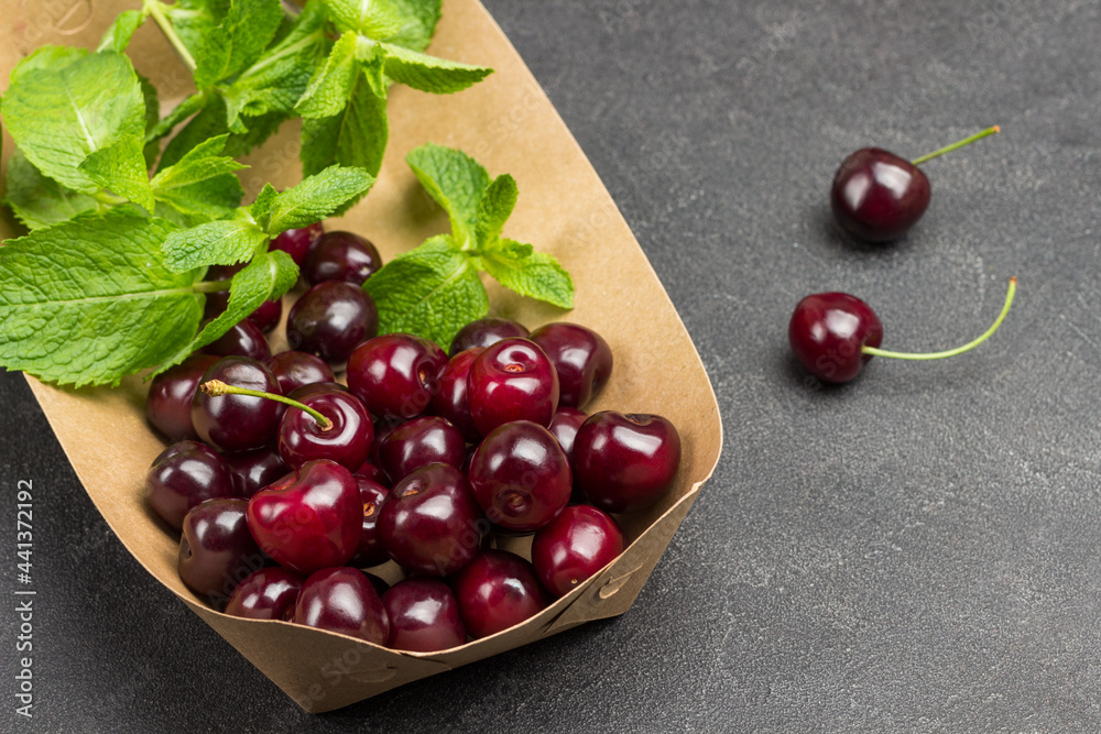 Sweet cherries and mint leaves in cardboard plate. Sweet cherries and mint leaves in cardboard plate.