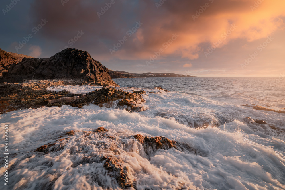 Waves of white foam cover the rocks on the Galdar coast at sunset. Gran Canaria. Canary Islands Waves of white foam cover the rocks on the Galdar coast at sunset. Gran Canaria. Canary Islands