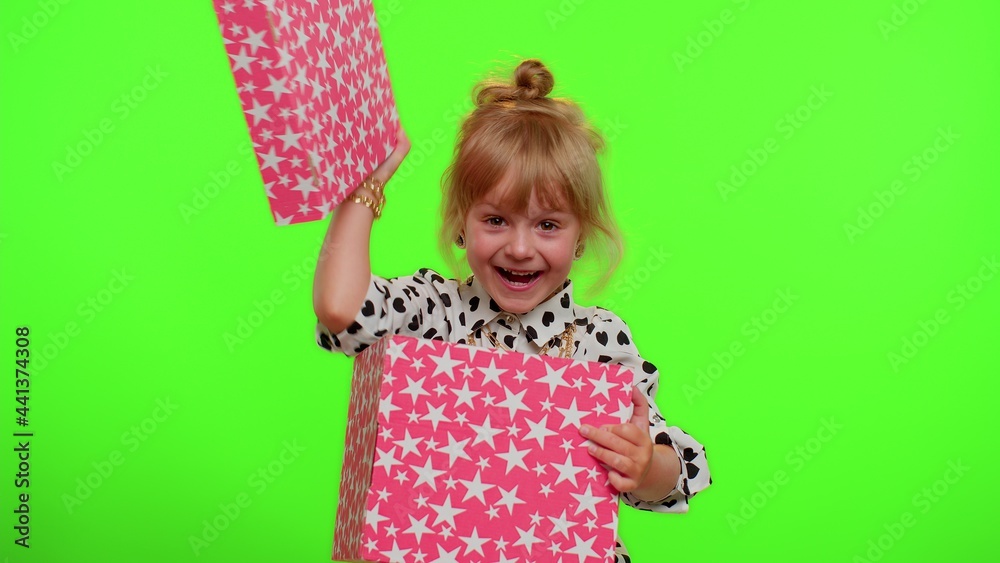 Cheerful stylish little child girl opening gift box, unwrapping birthday surprise and expressing great happiness amazement satisfied with best present bonus. Cute kid on chroma key wall background