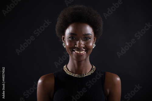 Close up portrait of smiling african-american woman with afro hairstyle on black studio background.