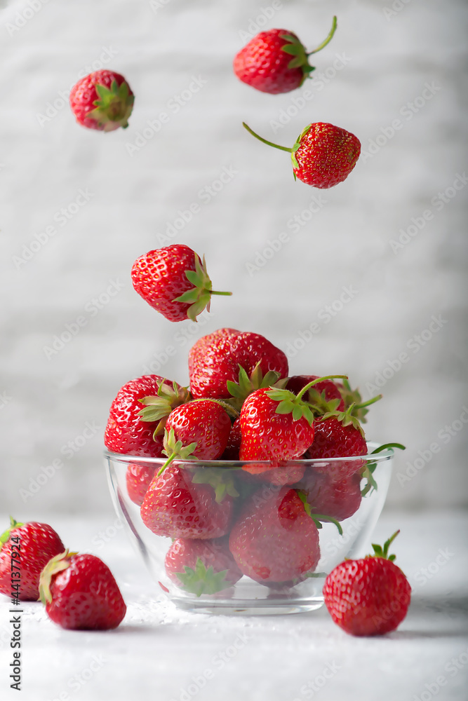 Φωτογραφία Levitating fresh ripe tasty strawberry in glass bowl on gray background
