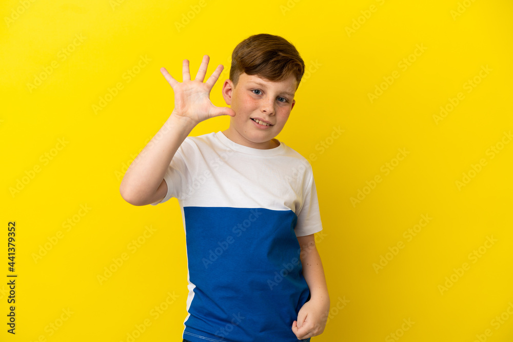 Little redhead boy isolated on yellow background counting five with fingers Little redhead boy isolated on yellow background counting five with fingers
