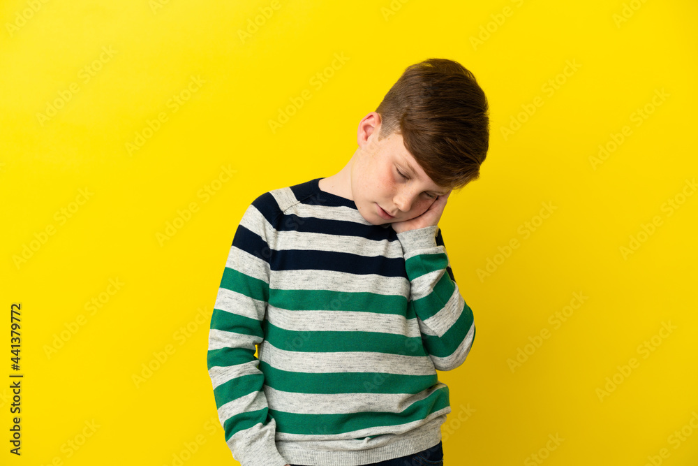 Little redhead boy isolated on yellow background with headache Little redhead boy isolated on yellow background with headache