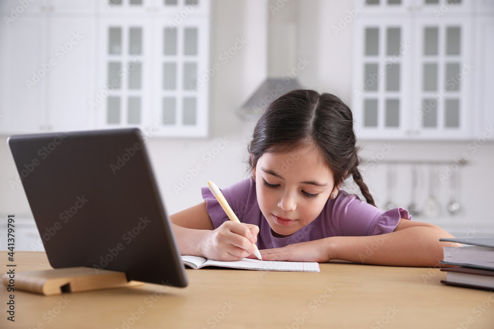 Little girl doing homework with modern tablet at home Little girl doing homework with modern tablet at home