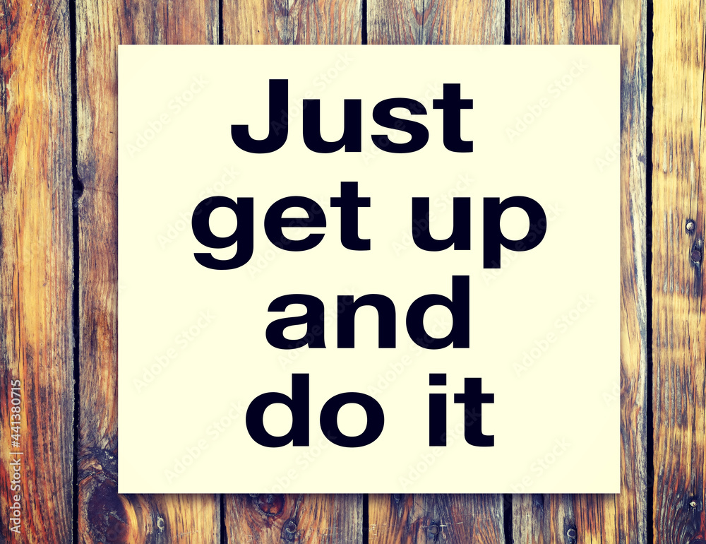 Motivational inscription on the sheet - Just get up and do it - against the background of a wooden table. Motivational inscription on the sheet - Just get up and do it - against the background of a wooden table.