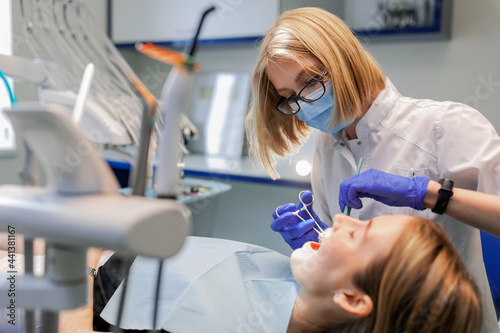 The dentist treats the patient's teeth. Puts braces on a girl. Dentist's office.