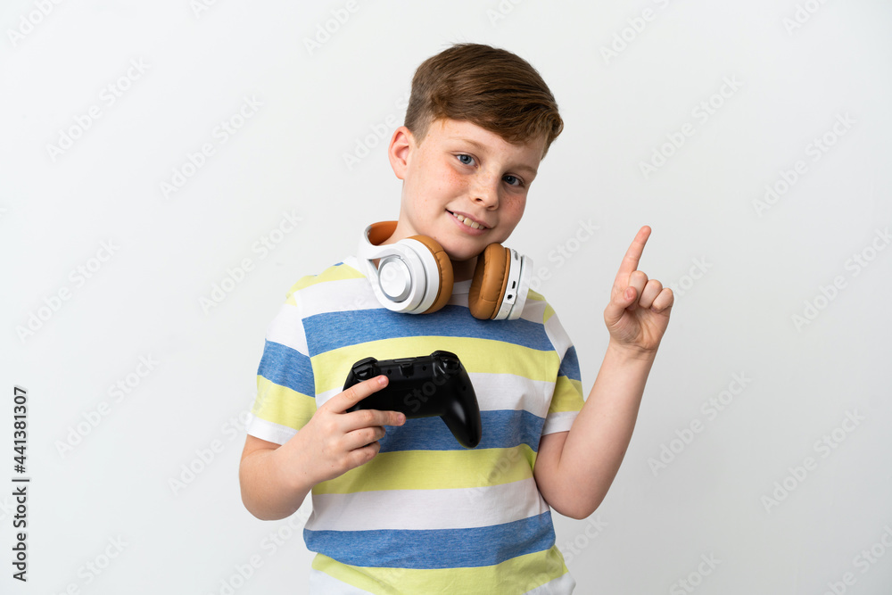 Little redhead boy holding a game pad isolated on white background showing and lifting a finger in sign of the best