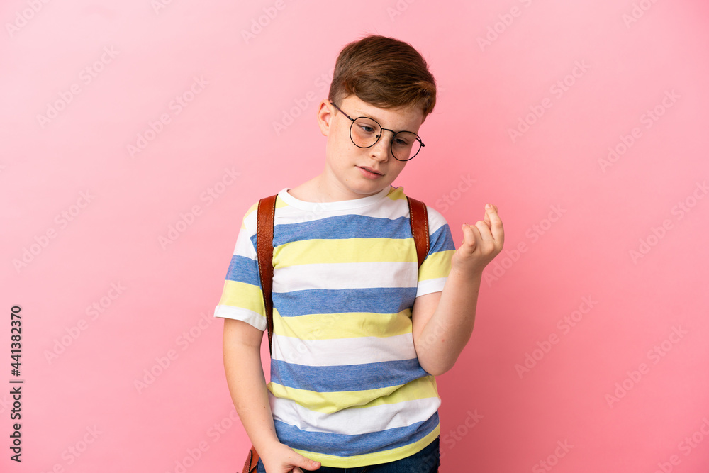 Little redhead caucasian boy isolated on pink background making money gesture Little redhead caucasian boy isolated on pink background making money gesture