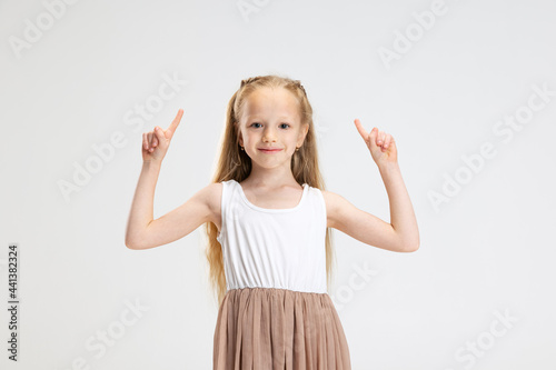 Half length portrait of cute little girl in modern stylish dress posing isolated on white studio background. Happy childhood concept.