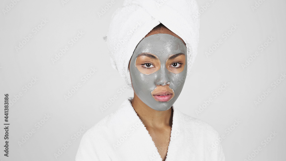 African american woman with clay mask on face and towel on head isolated on grey African american woman with clay mask on face and towel on head isolated on grey