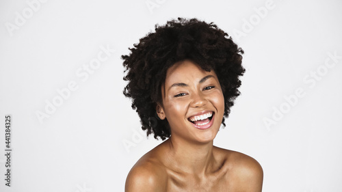 Positive african american woman with clean skin looking at camera isolated on grey