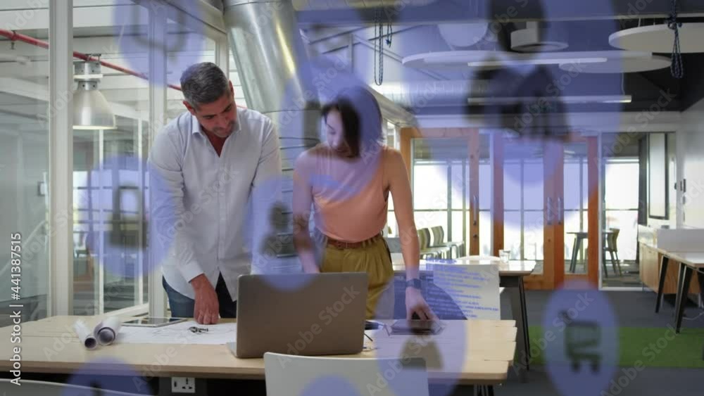 Animation of network of digital icons over business colleagues using laptop in office Animation of network of digital icons over business colleagues using laptop in office