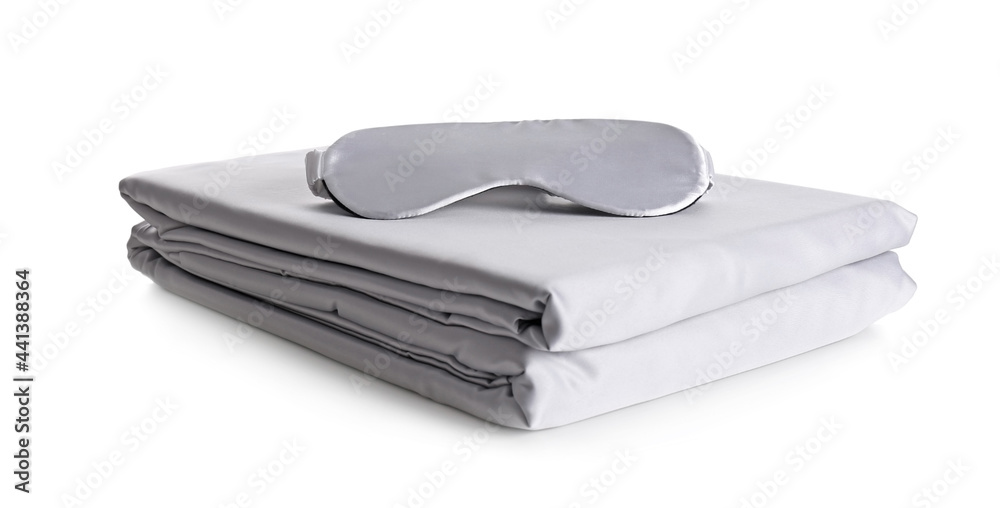 Stack of clean silky bed linen and sleeping mask isolated on white Stack of clean silky bed linen and sleeping mask isolated on white
