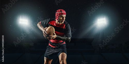 One caucasian man playing rugby on the stadium at stadium with flashlights. Cocept of sport, competition.