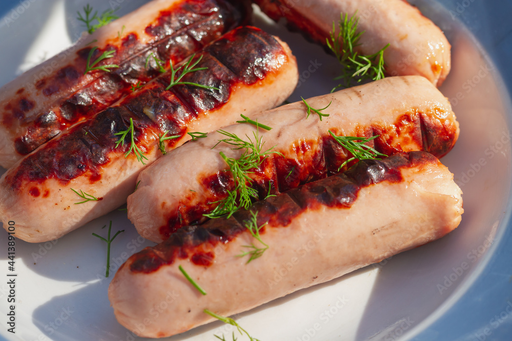 The sausages are grilled on a picnic grill and sprinkled with green dill