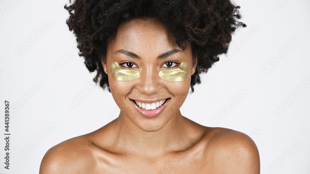 Smiling african american woman with golden eye patches isolated on grey Smiling african american woman with golden eye patches isolated on grey