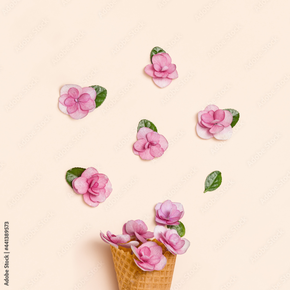 Waffle ice cream cone with pink small flowers and green leaves on millennial pink background. Minimal summer flat lay composition with blossoms Hydrangea. Waffle ice cream cone with pink small flowers and green leaves on millennial pink background. Minimal summer flat lay composition with blossoms Hydrangea.