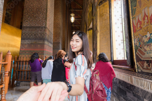 Asian women leading man hand follow travel in buddhist temple couple relationship