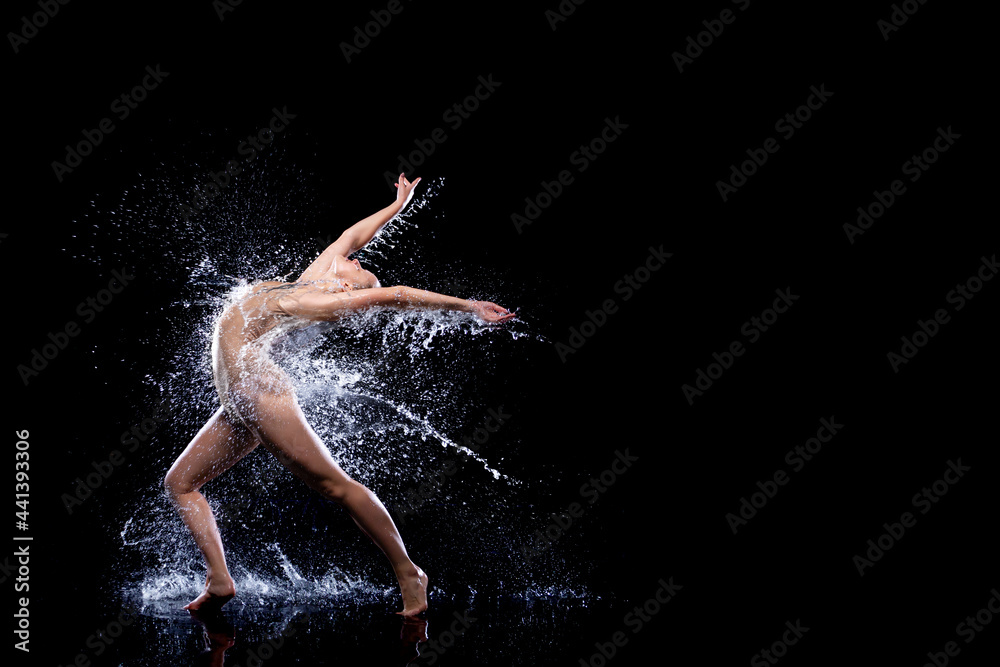 Slender woman in wet sports underwear dancing on surface of water. Ballet dancer is making tricks in liquid splashes. Athletic body is glisten in studio light. Freedom, freshness concept. Modern art.