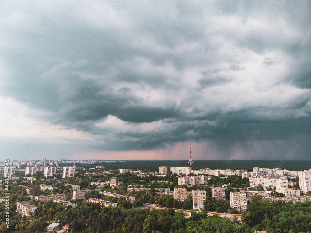 Aerial view on green Kharkiv city center Botanical garden and Pavlove Pole. Multistory buildings with telecommunication tower antenna with scenic rainy dark heavy clouds sky