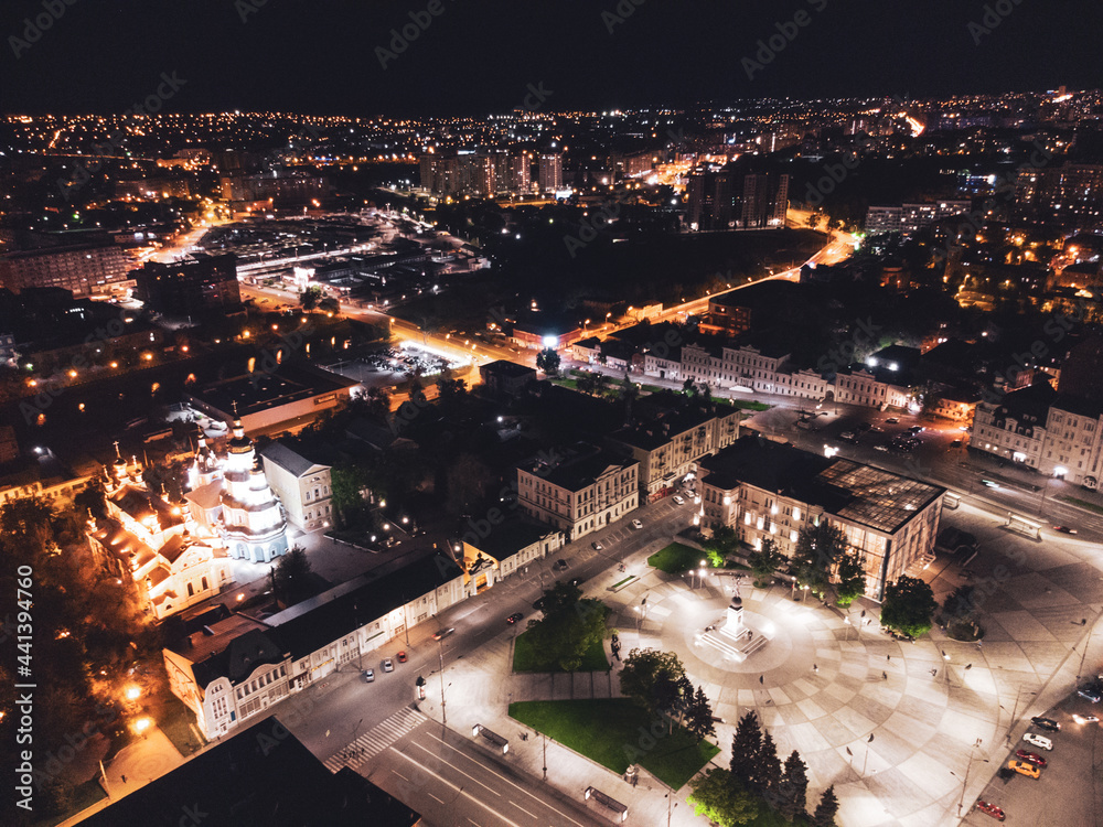 Night lights illuminated city aerial view. City center square (Maidan Konstytutsii) with historical museum, Svyato-Pokrovskyy Monastyr landmarks in Kharkiv, Ukraine