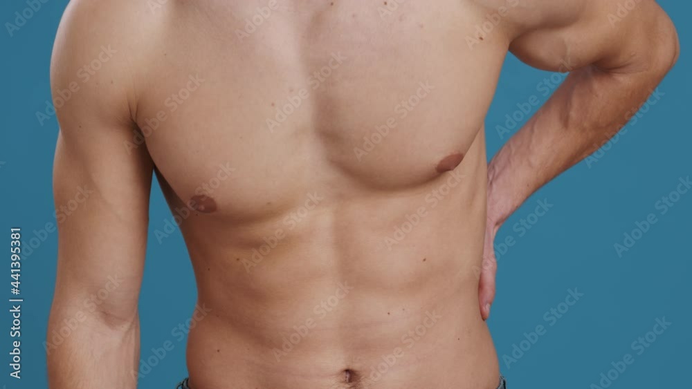 Kidney pain. Young unrecognizable caucasian man touching his lower back, suffering from acute pain, blue background Kidney pain. Young unrecognizable caucasian man touching his lower back, suffering from acute pain, blue background