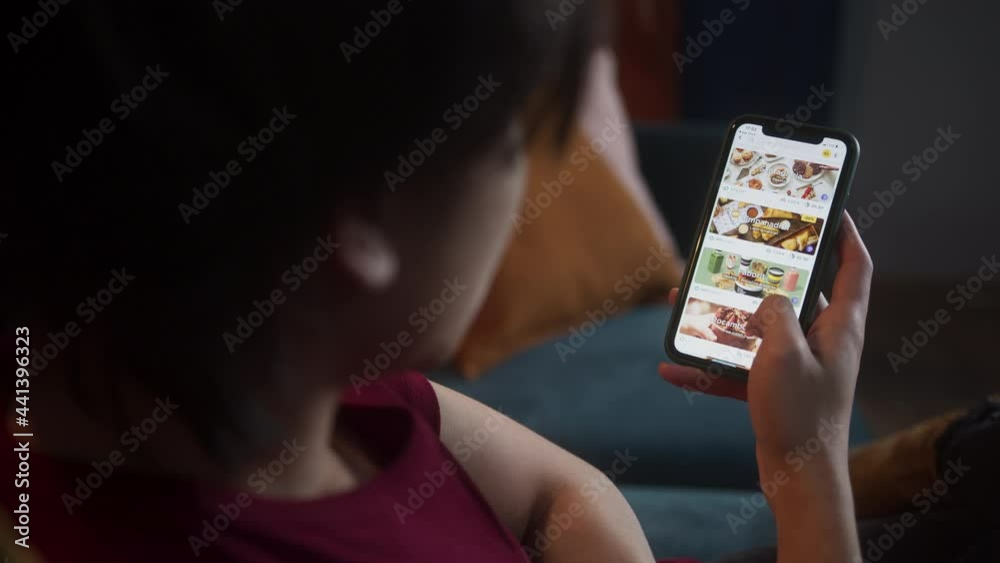 Asian man choosing a meal in online shop application, Black Friday week, shopping by phone, e-commerce payment, big marketplace. Young Korean student using food delivery.