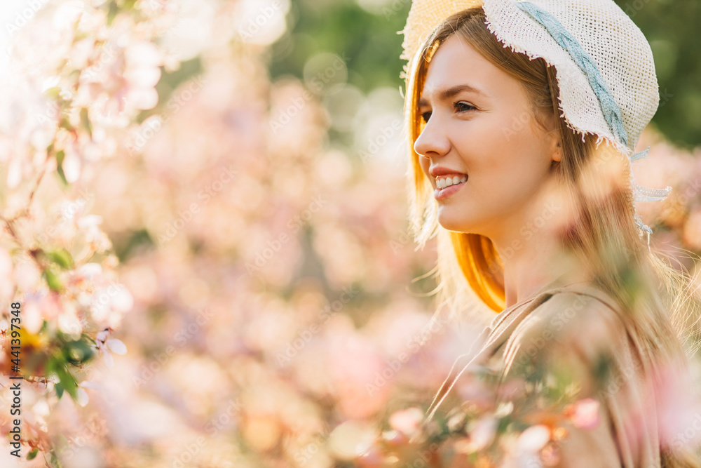 Fototapeta premium romantic image of tender young woman, in hat, happy smiling woman with spring flowers in the garden, spring concept