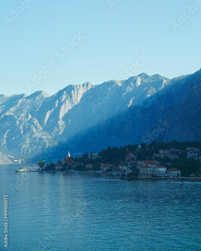 A view of Montenegro from the waters of the Adriatic Sea. Sunlight streaks across the mountainous cliffside