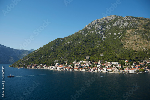 A view of the Montenegro coastline from the from a boat on the Adriatic Sea. A fishing village sits at the base of the mountainous cliffs