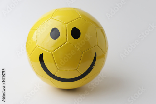 Yellow ball with smile face to play football on white background.