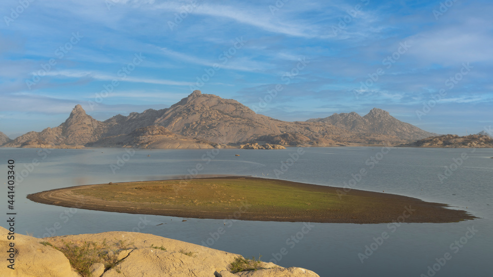 View of a small island in the middle of Jawai dam with clouds and blue sky in the background at Rajasthan India

