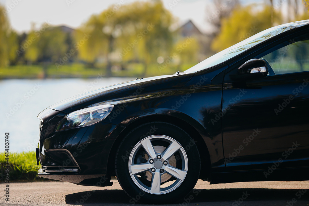 Car side view on the background of the lake and green threes. Car wheels and breaks close up. Car side view on the background of the lake and green threes. Car wheels and breaks close up.