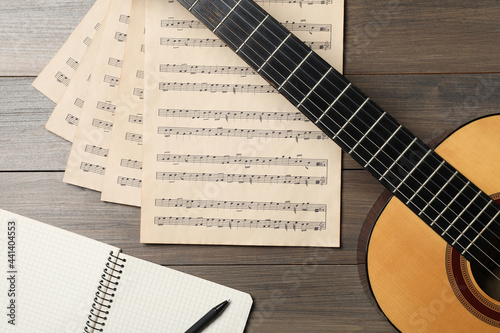 Composition with guitar and music notations on wooden table, flat lay