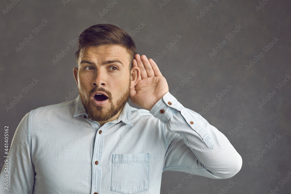 Omg I can hear them talk about something interesting. Curious attentive guy isolated on gray background puts hand to ear overhearing top secret information or listening to hot news and shocking gossip Omg I can hear them talk about something interesting. Curious attentive guy isolated on gray background puts hand to ear overhearing top secret information or listening to hot news and shocking gossip