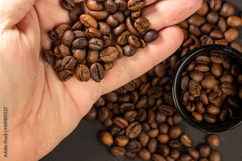 Coffee beans of quality roasted coffee in a man hand, selective focus.