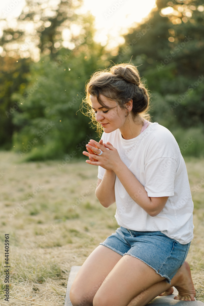 Woman closed her eyes, praying in a field during beautiful sunset. Hands folded in prayer concept for faith, spirituality and religion. Woman closed her eyes, praying in a field during beautiful sunset. Hands folded in prayer concept for faith, spirituality and religion.