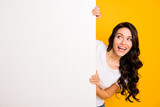 Portrait of lovely curious cheerful wavy-haired girl holding big board copy space look idea isolated over bright yellow color background
