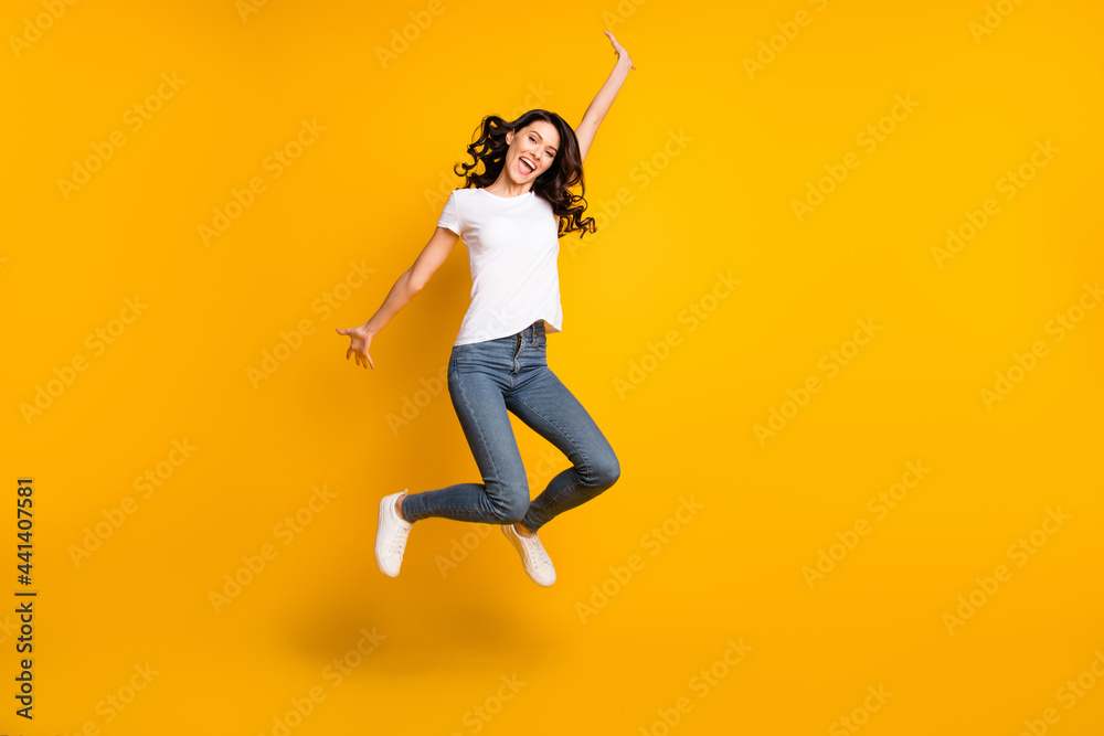 Full length body size view of attractive cheerful girl jumping having fun good day isolated over bright yellow color background Full length body size view of attractive cheerful girl jumping having fun good day isolated over bright yellow color background