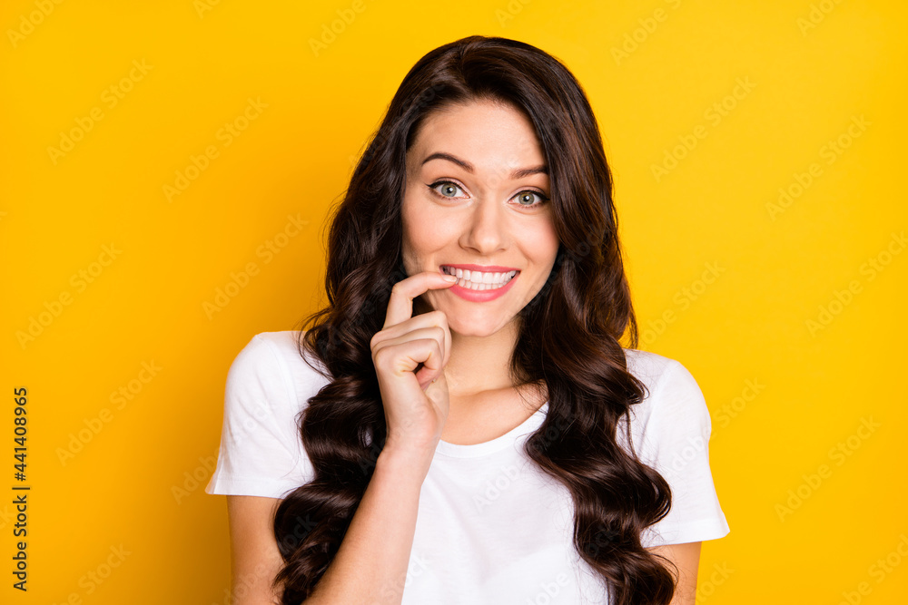 Photo of adorable tricky young lady dressed white t-shirt smiling biting finger isolated yellow color background Photo of adorable tricky young lady dressed white t-shirt smiling biting finger isolated yellow color background