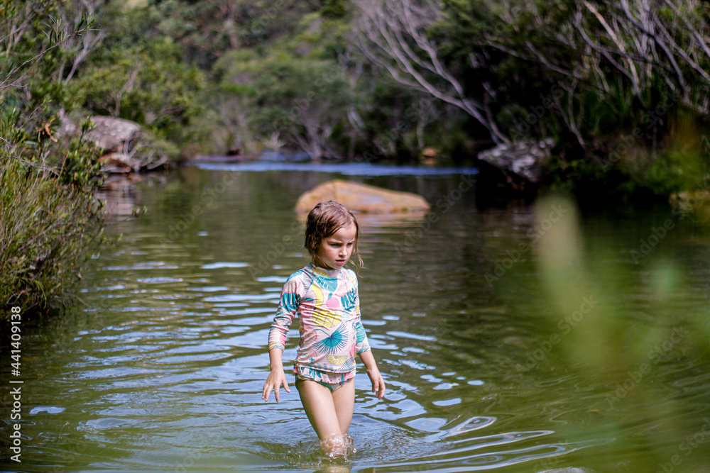 Girl wearing a swimsuit exploring a river by herself Girl wearing a swimsuit exploring a river by herself