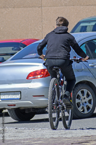 A young man rides a bicycle on a city street on a summer day